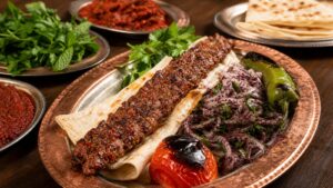 Adana kebap, közlenmiş biber, lavaş ve soğan salatası ile geleneksel servis